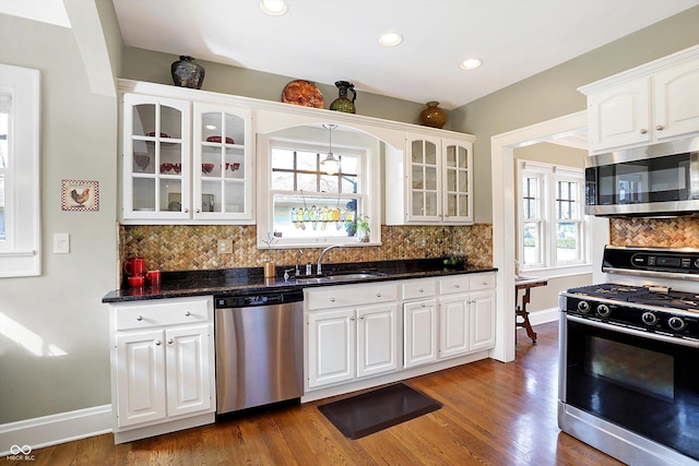 kitchen featuring appliances with stainless steel finishes, glass insert cabinets, a sink, and white cabinetry