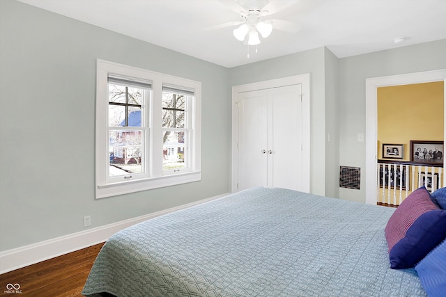 bedroom with dark wood-type flooring, a closet, ceiling fan, and baseboards