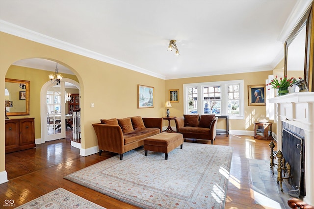 living area with arched walkways, a fireplace with raised hearth, hardwood / wood-style floors, and baseboards