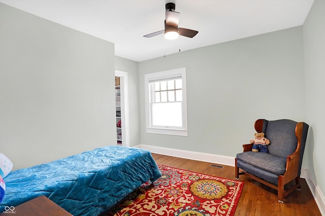 bedroom featuring a ceiling fan, visible vents, baseboards, and wood finished floors