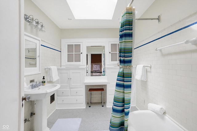 full bath with shower / bath combo, a skylight, and tile walls