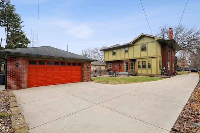 view of front of home featuring an outbuilding, brick siding, a shingled roof, driveway, and a chimney