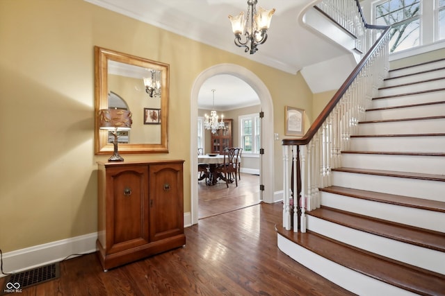 entryway with a chandelier, arched walkways, visible vents, and dark wood finished floors