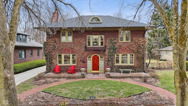 colonial inspired home featuring a chimney, fence, a front lawn, and brick siding