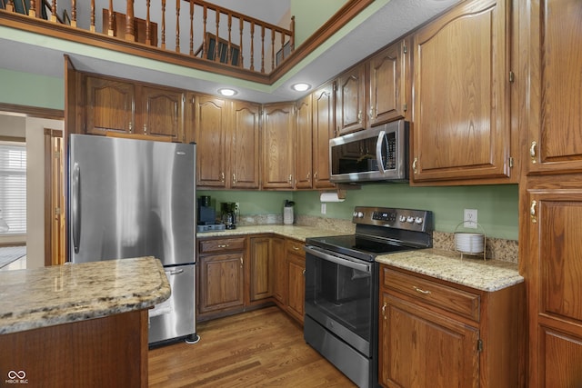 kitchen featuring appliances with stainless steel finishes, light stone counters, and light hardwood / wood-style flooring