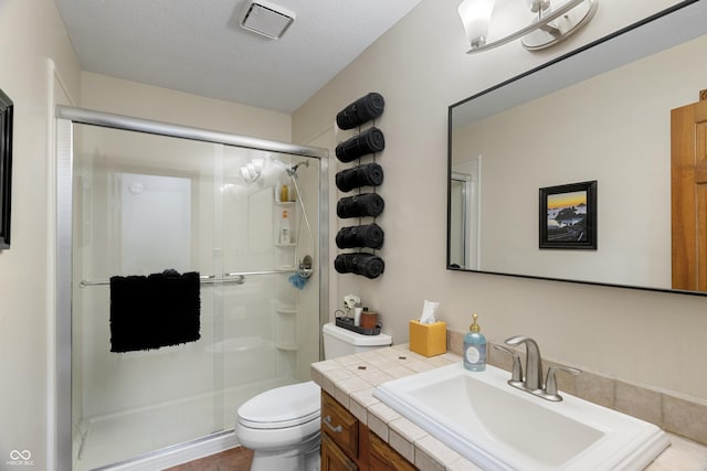 bathroom featuring vanity, walk in shower, a textured ceiling, and toilet