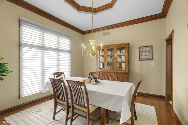 dining room featuring crown molding, wood-type flooring, and a notable chandelier