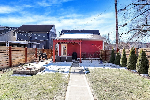 back of property with a pergola, a yard, and a fire pit