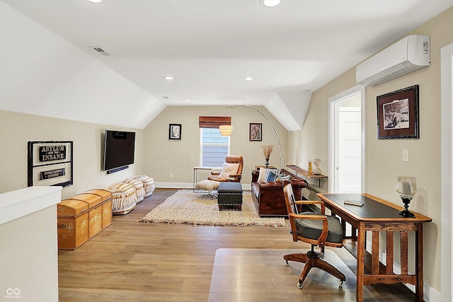 office with vaulted ceiling, a wall unit AC, and light hardwood / wood-style flooring