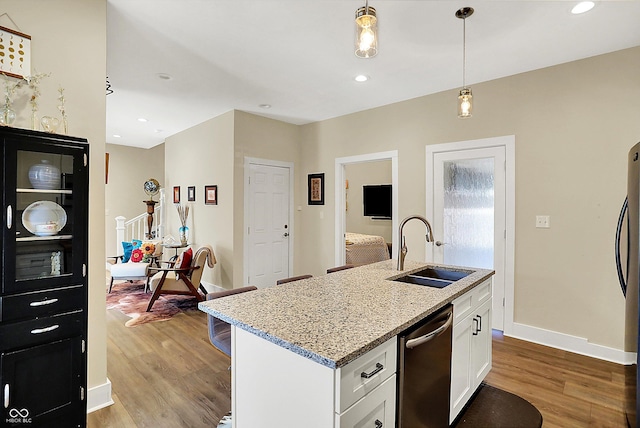 kitchen featuring sink, white cabinets, stainless steel dishwasher, a center island with sink, and light hardwood / wood-style flooring