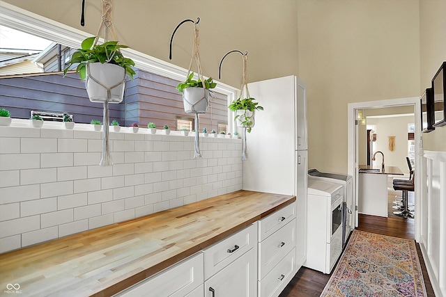 kitchen featuring dark wood-type flooring, butcher block counters, white cabinetry, tasteful backsplash, and washing machine and clothes dryer