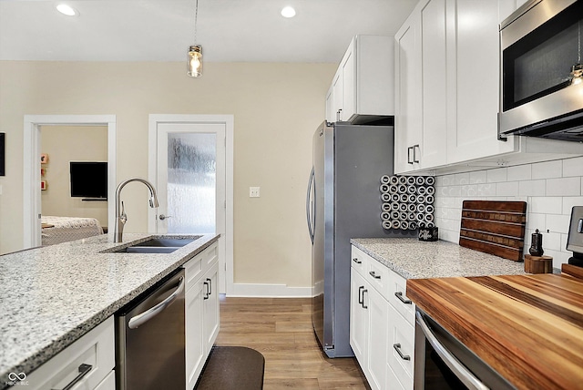 kitchen featuring sink, white cabinetry, wooden counters, decorative light fixtures, and stainless steel appliances