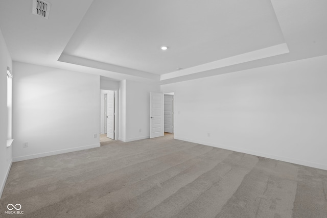 empty room with light carpet and a raised ceiling