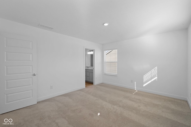 unfurnished bedroom with light colored carpet and ensuite bathroom