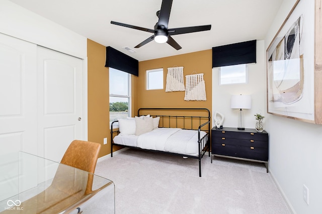 bedroom featuring light carpet, ceiling fan, and a closet