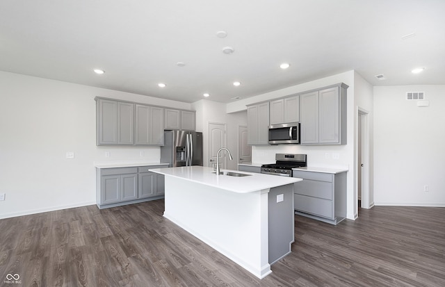 kitchen featuring appliances with stainless steel finishes, gray cabinets, sink, and a center island with sink