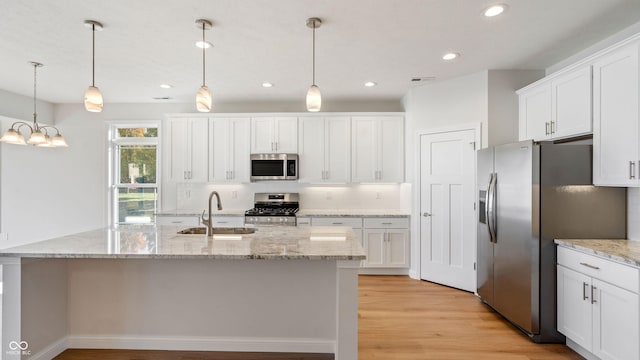 kitchen featuring stainless steel appliances, white cabinetry, sink, and decorative light fixtures