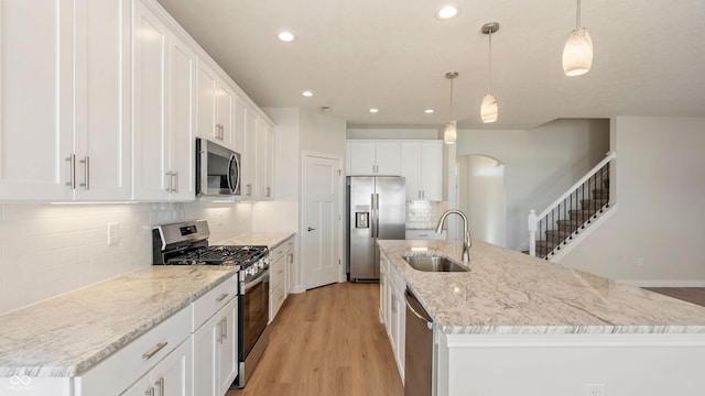 kitchen featuring hanging light fixtures, an island with sink, appliances with stainless steel finishes, and sink