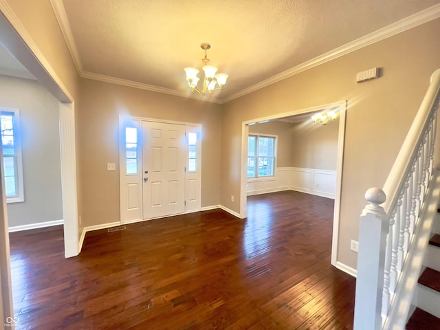 entrance foyer with dark wood-type flooring, crown molding, and a chandelier