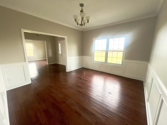 spare room featuring crown molding, dark wood-type flooring, and a chandelier