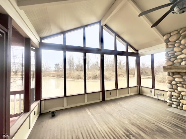 unfurnished sunroom featuring a water view, ceiling fan, a wealth of natural light, and vaulted ceiling with beams