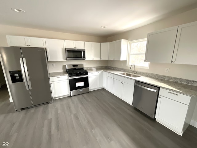 kitchen featuring sink, wood-type flooring, stainless steel appliances, and white cabinets