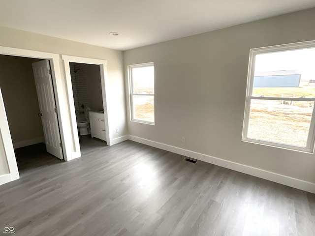 unfurnished bedroom with hardwood / wood-style flooring and ensuite bath