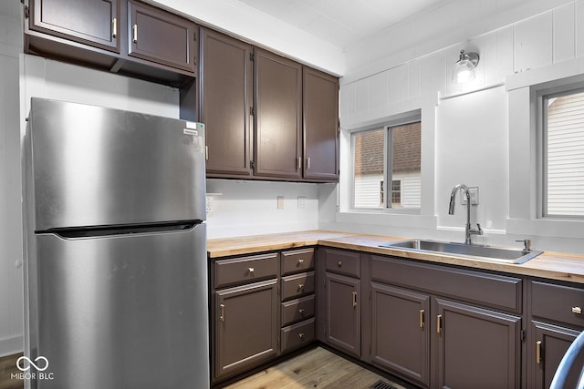 kitchen featuring wooden counters, sink, stainless steel fridge, and light wood-type flooring