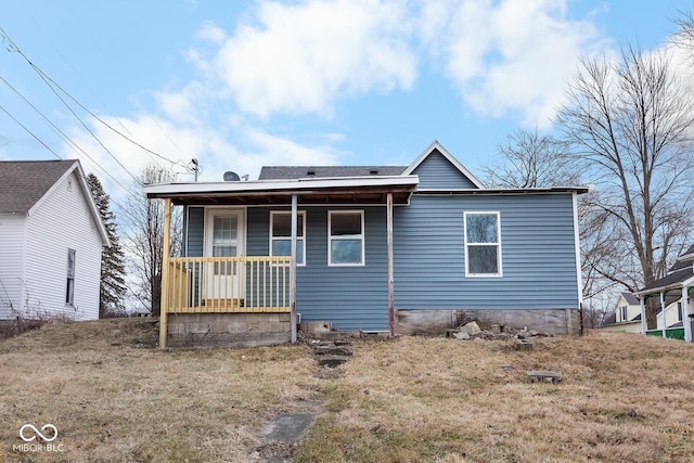 rear view of house featuring covered porch and a lawn