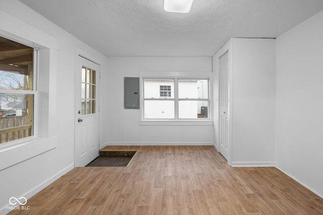 interior space with a textured ceiling, electric panel, and light wood-type flooring