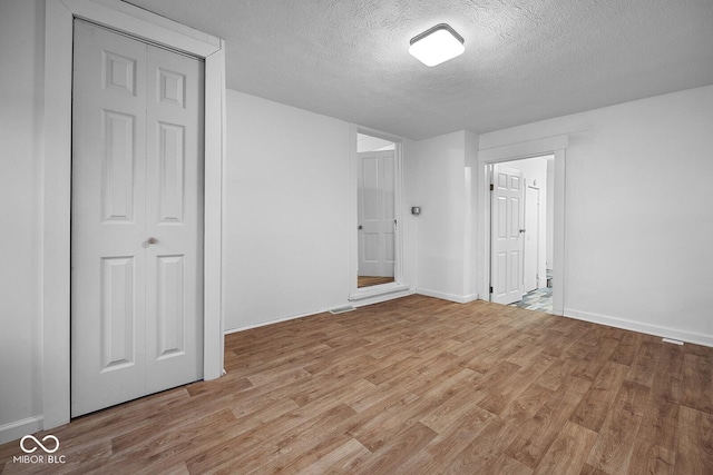 unfurnished bedroom with a textured ceiling and light hardwood / wood-style flooring