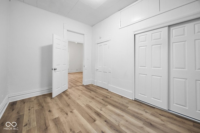 unfurnished bedroom with light wood-type flooring and a closet