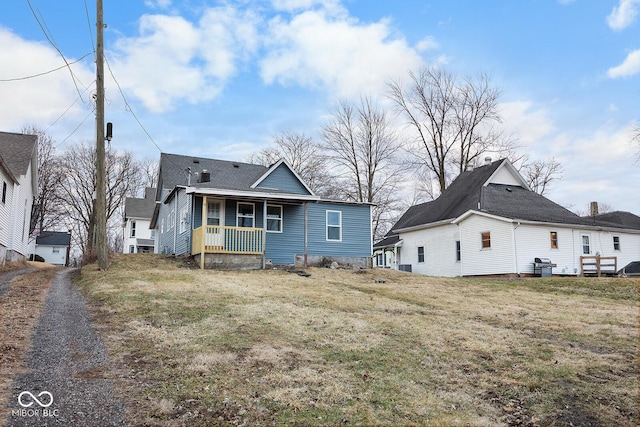 rear view of house with a lawn and a porch