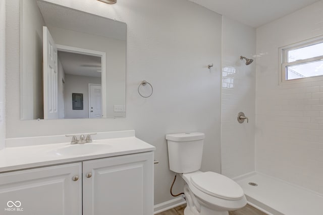 bathroom featuring vanity, toilet, and a tile shower