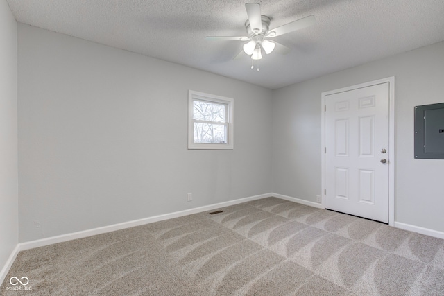 carpeted spare room with ceiling fan, electric panel, and a textured ceiling