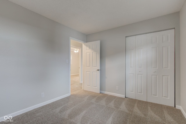 unfurnished bedroom featuring carpet floors, a textured ceiling, and a closet