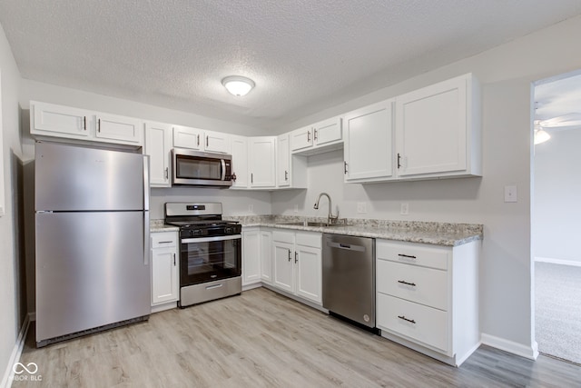 kitchen with white cabinetry, appliances with stainless steel finishes, light hardwood / wood-style floors, and sink