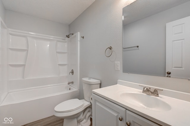 full bathroom featuring  shower combination, vanity, wood-type flooring, a textured ceiling, and toilet