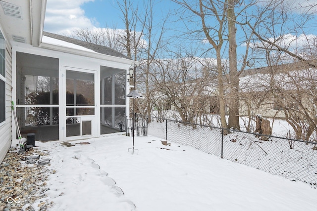 snowy yard featuring fence and a sunroom