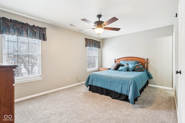 carpeted bedroom featuring a ceiling fan, visible vents, and baseboards