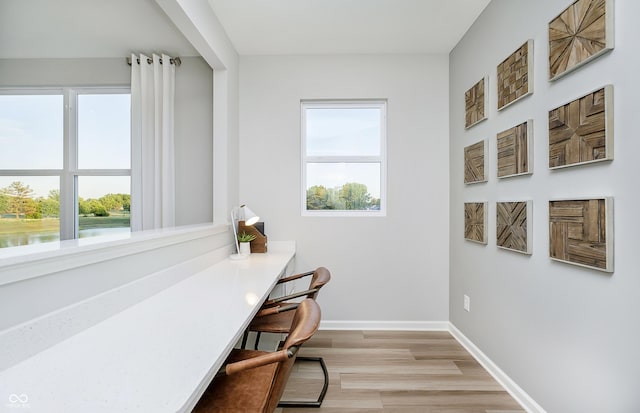 office featuring a water view, light hardwood / wood-style floors, and a wealth of natural light