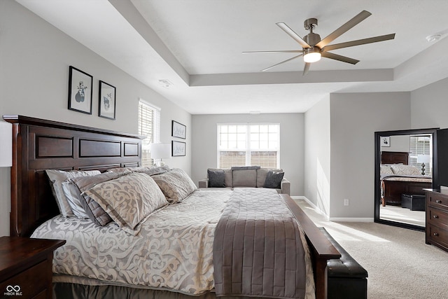 bedroom with ceiling fan, multiple windows, a tray ceiling, and light carpet