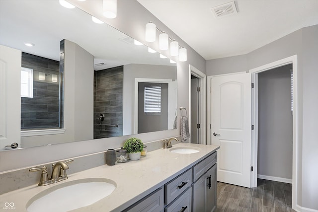 bathroom featuring tiled shower, vanity, and wood-type flooring