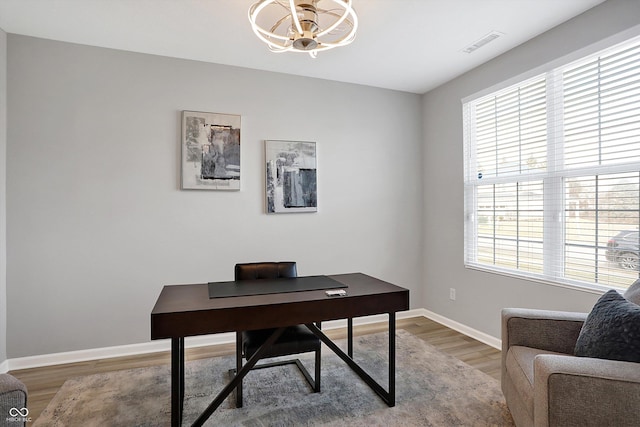 office area with an inviting chandelier, baseboards, visible vents, and light wood-type flooring