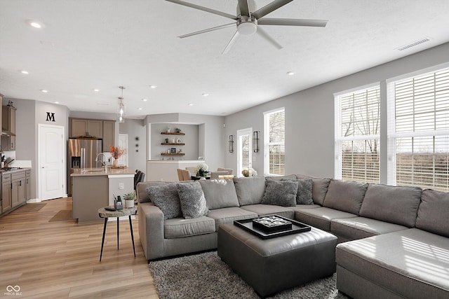 living room featuring ceiling fan, sink, a textured ceiling, and light hardwood / wood-style floors