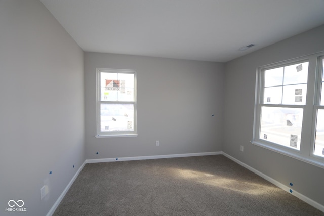 carpeted spare room with plenty of natural light, visible vents, and baseboards