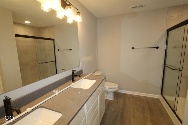 bathroom featuring wood finished floors, a sink, and a shower stall