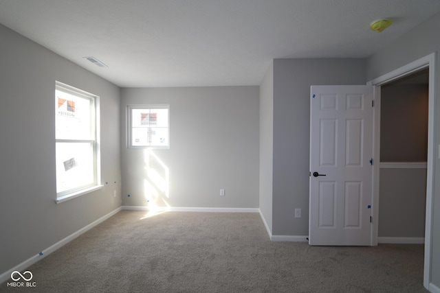 carpeted empty room featuring visible vents and baseboards