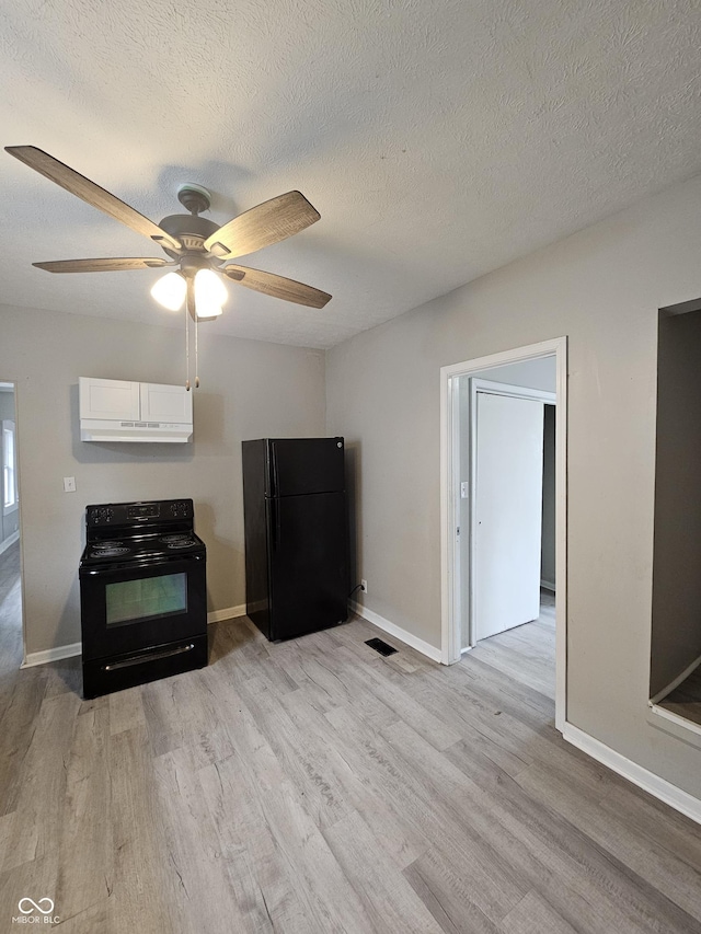 kitchen with a textured ceiling, white cabinets, light hardwood / wood-style floors, and black appliances