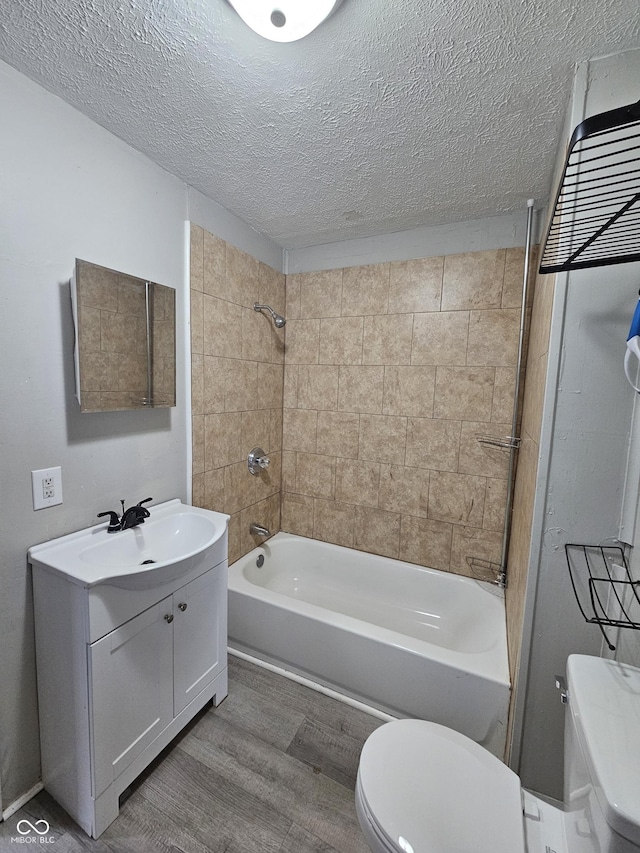 full bathroom with tiled shower / bath combo, vanity, wood-type flooring, a textured ceiling, and toilet